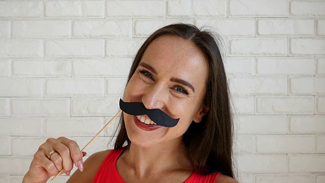 露齿微笑的女人拿着纸胡子玩视频下载