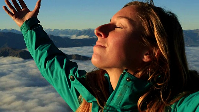 这是一个在山顶上张开双臂的女人的肖像视频素材