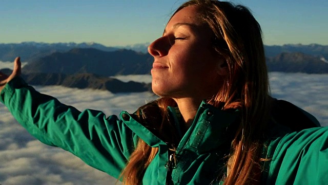 这是一个在山顶上张开双臂的女人的肖像视频素材