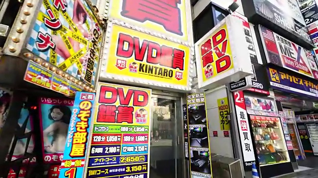 在歌舞伎町新宿的街道上，镜头捕捉到了许多餐馆、酒吧和成人商店的招牌。视频素材