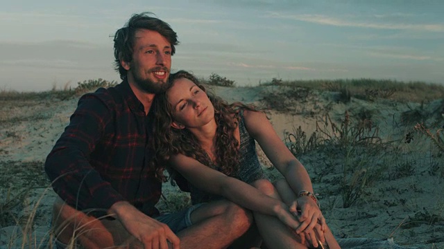 在法国南部大西洋海滩的沙丘上，一对相爱的年轻夫妇在一起享受时光，观看日落视频下载