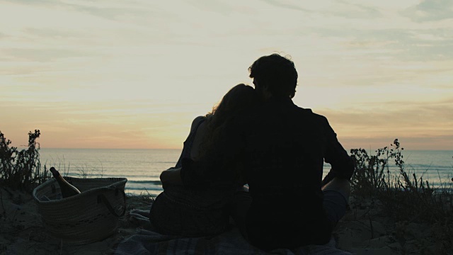 在法国南部大西洋海滩的沙丘上，一对相爱的年轻夫妇在一起享受时光，观看日落视频素材