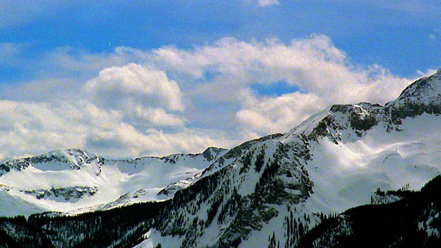 宽镜头延时滚动云在蓝天后面的雪山/落基山脉附近特柳赖德，科罗拉多州视频素材