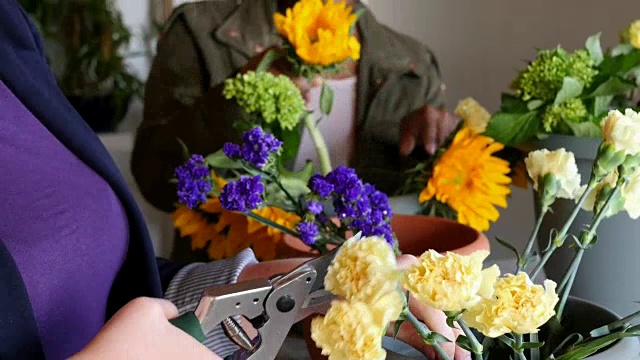快乐的年轻女性在花店工作，制作鲜花束视频下载