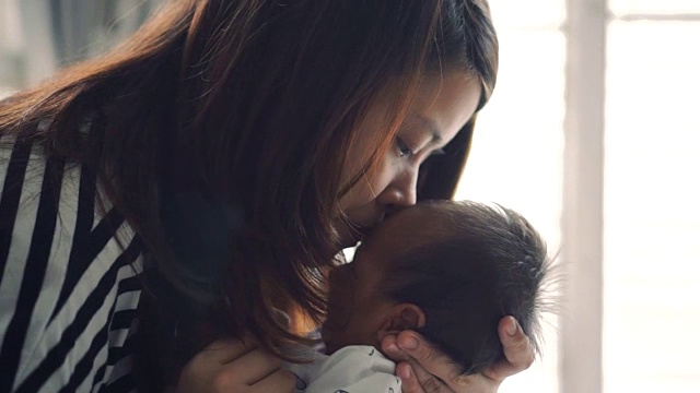 一个女人抱着一个婴儿亲吻他视频下载