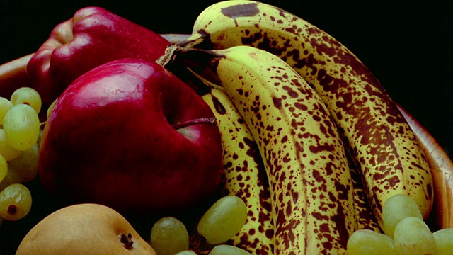 近距离的时间流逝香蕉，苹果，梨和葡萄成熟+开始腐烂在黑色背景视频下载