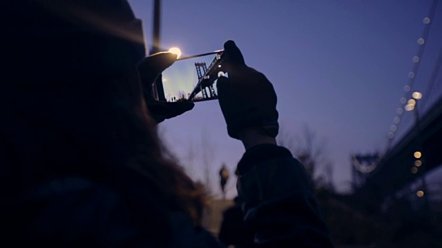 女游客用智能手机拍摄日落视频素材