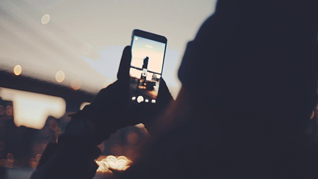 年轻女子在河边用智能手机拍照视频下载