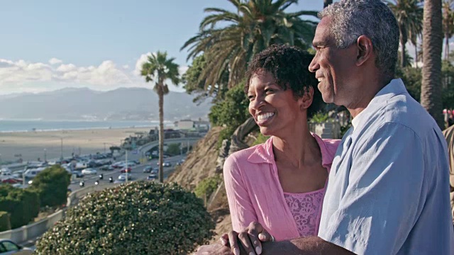 一对快乐的非裔美国夫妇在海滨木板路上聊天视频素材