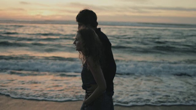 在法国南部大西洋的海滩上，一对相爱的年轻夫妇在一起享受时光，脚在水里散步视频素材