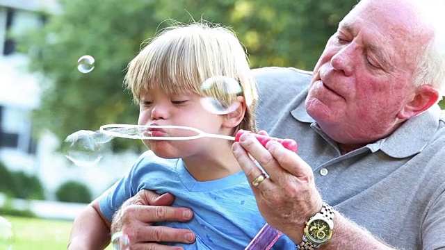 患有唐氏综合症的男孩和他的祖父吹泡泡视频素材