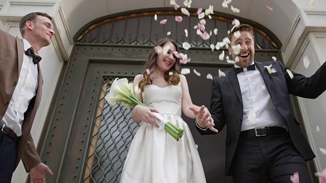 SLO MO新婚夫妇离开教堂时被玫瑰簇拥视频素材