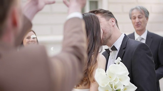 新婚夫妇亲吻，客人们向他们扔花瓣视频素材