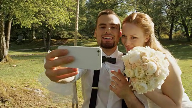 一对新婚夫妇在阳光明媚的公园里用智能手机拍秋千视频下载