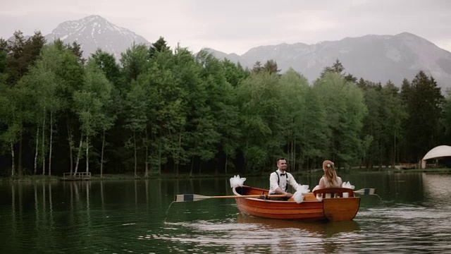 SLO MO新娘和她的新郎乘坐一艘船穿过一个湖视频素材
