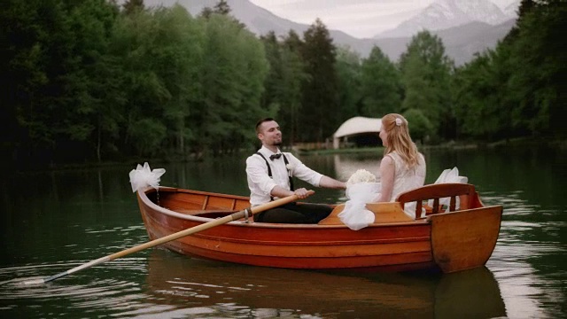 新娘和新郎在湖上的小船上接吻视频素材