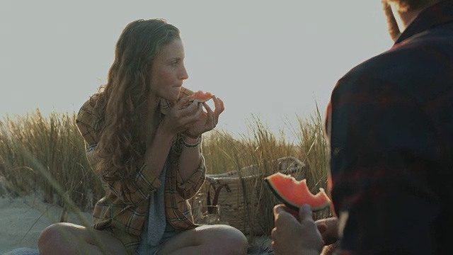 在法国南部的大西洋海滩上，一对相爱的年轻夫妇在一起享受时光，吃着西瓜视频素材