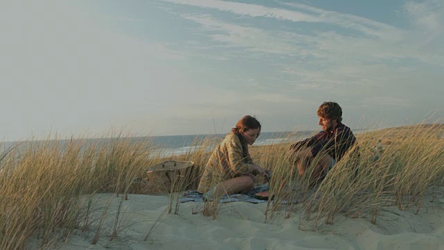 年轻的情侣在享受时间在一起，吃西瓜，有野餐在一个荒芜的海滩在大西洋在法国南部的沙丘视频素材