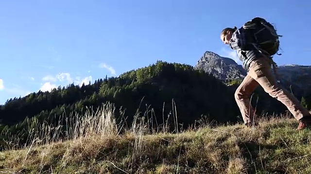 一名男性徒步旅行者朝着日出的方向走进了山上的草地视频素材