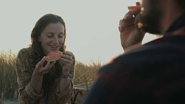 年轻的情侣在享受时间在一起，吃西瓜，有野餐在沙滩上在大西洋在法国南部视频素材