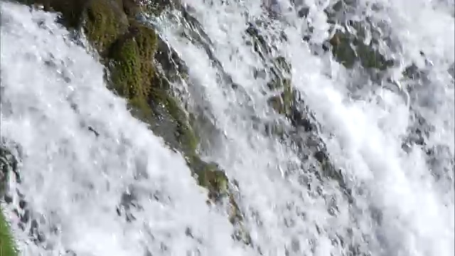 瀑布流下长满苔藓的岩石的特写镜头视频素材
