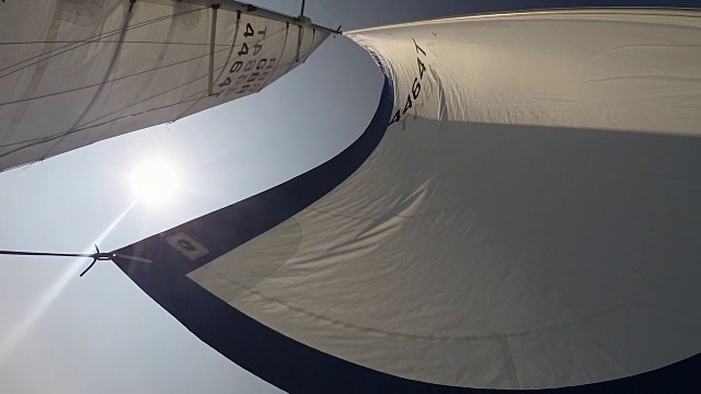 低角度拍摄的太阳照耀在帆板上的一艘游艇航行远离英格兰，英国。视频下载