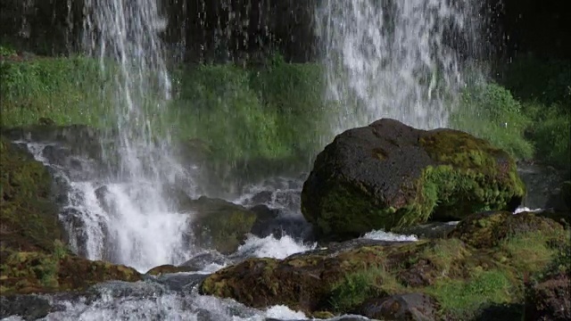 瀑布从长满苔藓的岩石上流下的特写镜头视频素材