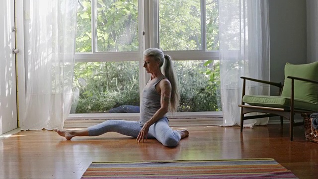 成熟的白人女人在客厅地板上练瑜伽视频素材