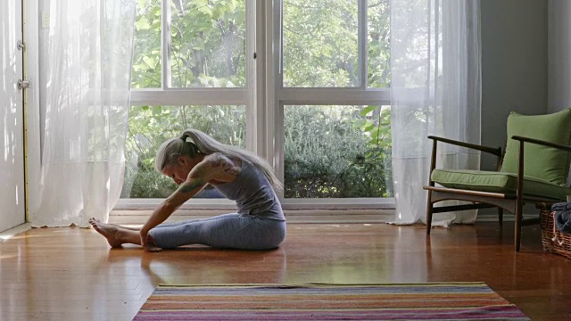 成熟的白人女人在客厅地板上练瑜伽视频素材