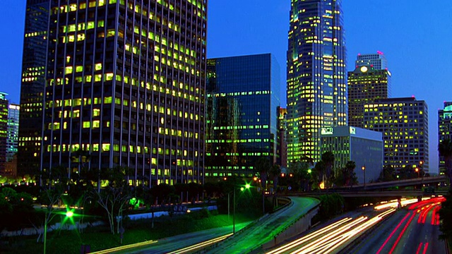 高角度广角拍摄时间流逝高速公路上的交通与办公大楼的背景在晚上/加州洛杉矶视频素材