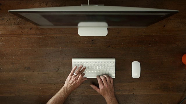 头顶的桌子上有台式电脑和男性的手打字视频素材