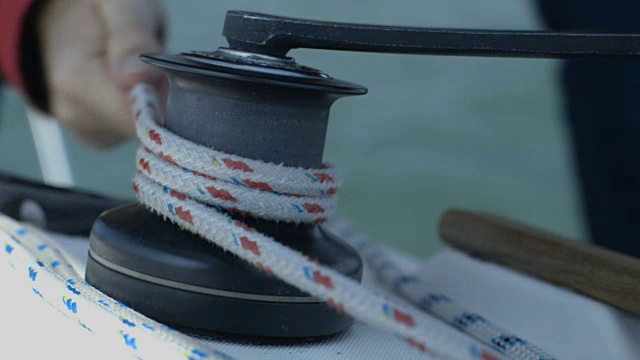 一个男人在移动的游艇上摇动绞车的极端特写镜头，英国。视频素材
