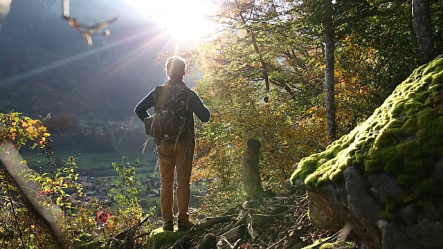 一名男性徒步旅行者走过山村上方的秋日森林视频素材