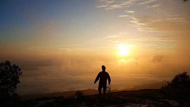 一个徒步旅行者在山顶伸展手臂视频素材