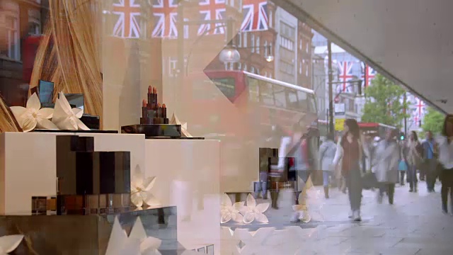 在牛津街一家百货商店的橱窗里，一个软焦点的展示在玻璃上反映了牛津街的购物者和通勤者视频素材