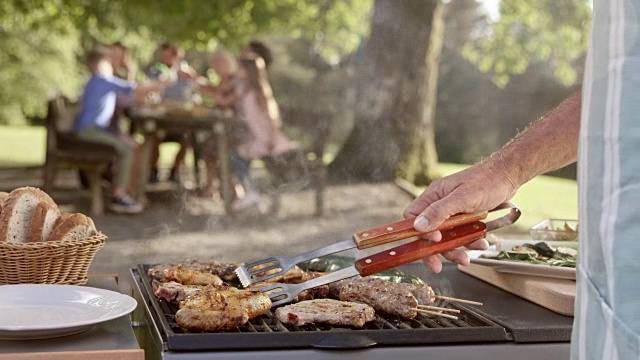 SLO MO Man在家庭野餐时在烤架上翻肉视频素材