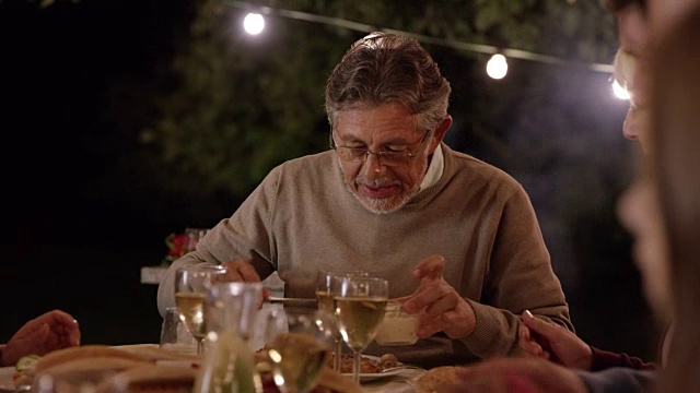 晚上，一个老人和他的家人在野餐桌上视频素材