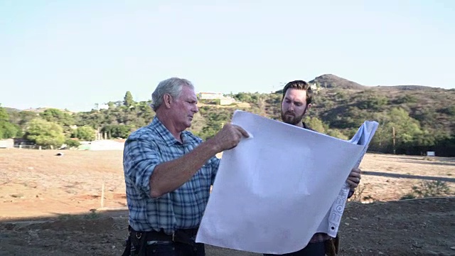 MS TS两个人在一座在建的房子前讨论计划视频素材