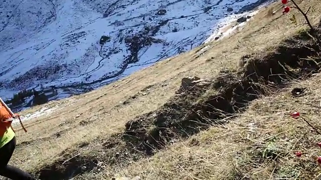 女性徒步者沿着山坡下山，身后是雪峰视频素材