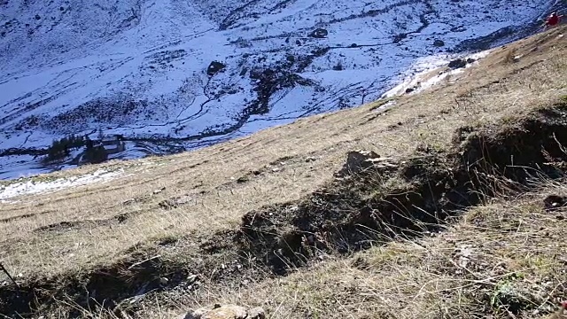 女性徒步者攀登山坡上的小径，后面是雪峰视频素材