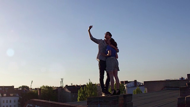一对年轻夫妇在城市的屋顶上自拍视频素材