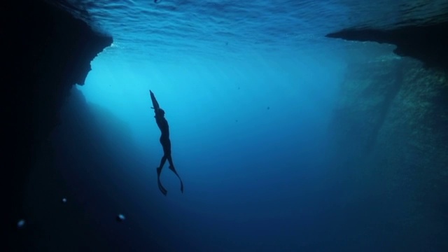 自由潜水者在蓝色的水中潜水视频素材
