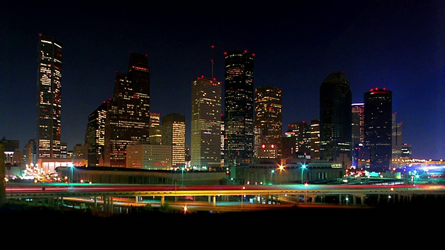 宽镜头延时交通高速公路与休斯顿天际线的背景在晚上/德克萨斯视频素材