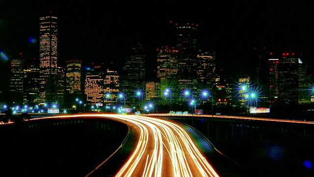 宽镜头延时交通高速公路与休斯顿天际线的背景在晚上/德克萨斯视频素材