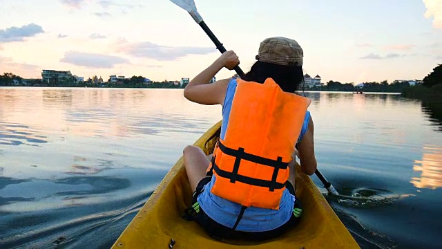 黄昏时分在湖上划皮艇的女子视频下载