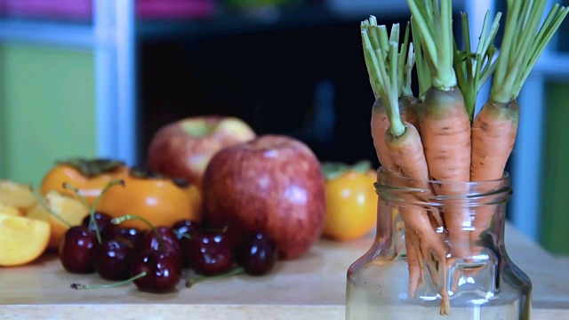 胡萝卜在玻璃罐中越过各种水果模糊的背景视频素材