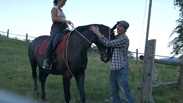 女人在乡村牧场骑马，而男人在一旁观看视频下载