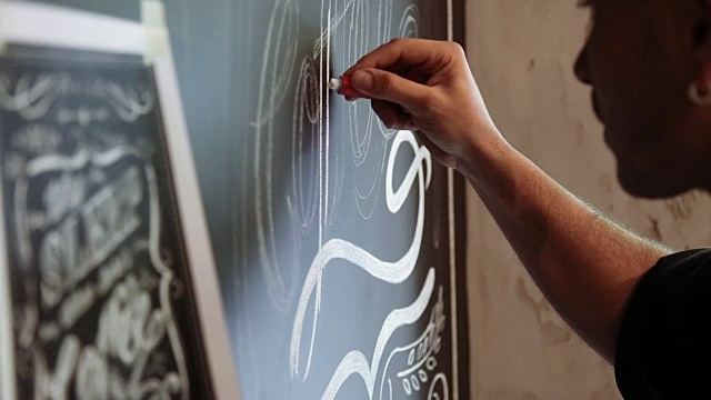 街头艺术家正在咖啡馆的黑色墙壁上用粉笔涂鸦视频下载