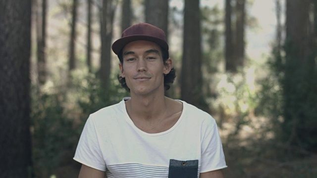 一个年轻人在森林里徒步旅行，对着镜头微笑视频素材