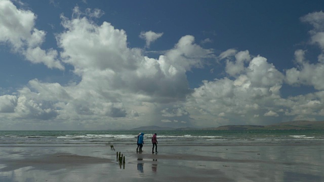 人们在爱尔兰克里郡的罗斯贝海滩遛狗，海浪，壮观的云彩视频下载